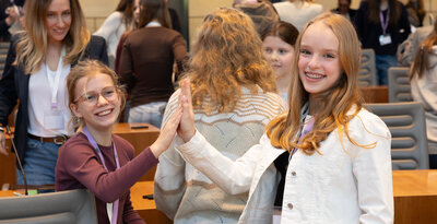 Zwei Schüler:innen im Landtag NRW, die abklatschen und in die Kamera lächeln